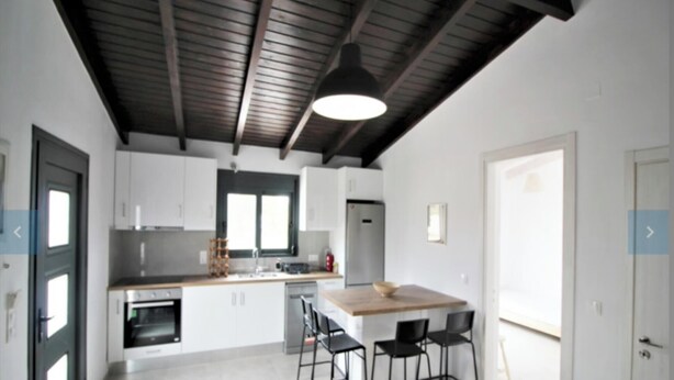 Una cocina moderna con armarios blancos, encimera de madera y una isla central con taburetes de bar.