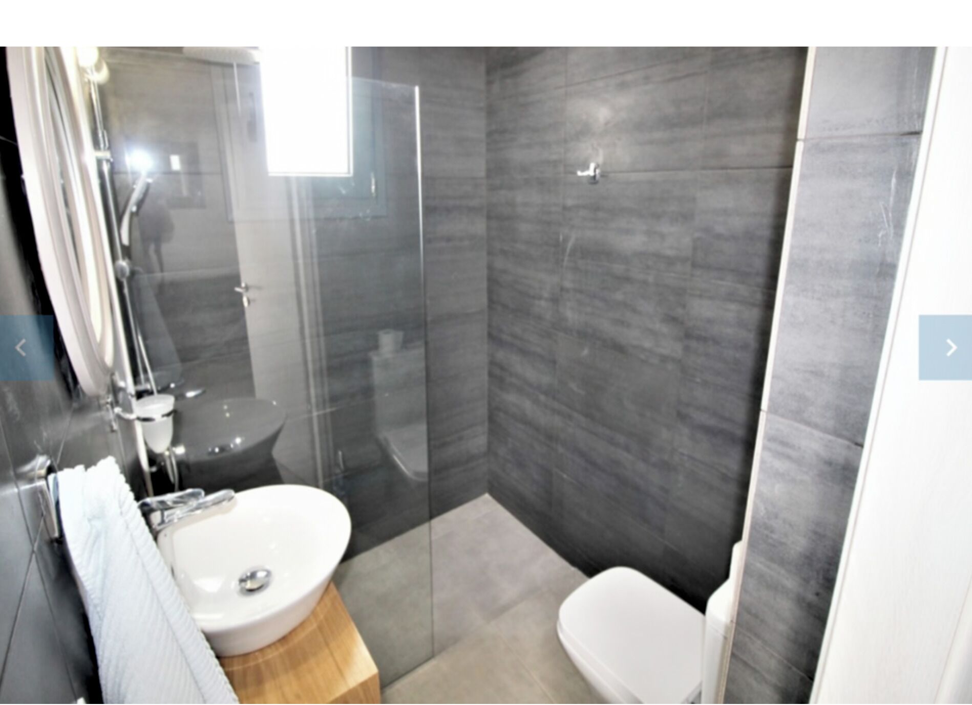 A modern bathroom with a glass-enclosed shower, a white sink, and a toilet.