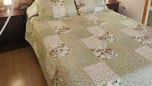 A bedroom with a stone wall, a quilted bedspread, two pillows, and bedside lamps.