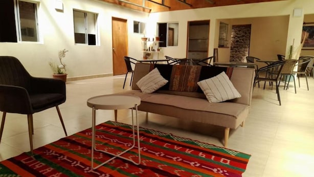 A living room with a sofa, chairs, a small table, and a patterned rug.