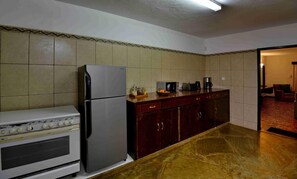 A kitchen with a stove, refrigerator, microwave, and wooden cabinets. - Mnarani Beach Club (Kilifi)