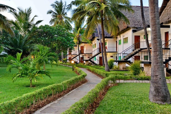 A resort with a pathway, palm trees, and a building with multiple balconies and staircases. - Mnarani Beach Club (Kilifi)