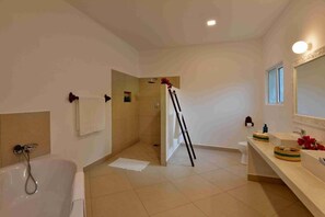 Une salle de bain moderne équipée d’une baignoire, d’une douche et d’un meuble-lavabo avec un miroir.