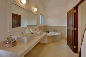 Ein Badezimmer mit zwei Waschbecken, einer Badewanne und einem großen Spiegel.