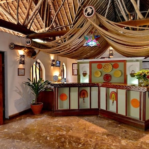 A reception area with a woven ceiling, a reception desk, and decorative plates on the wall. - Mnarani Beach Club (Kilifi)