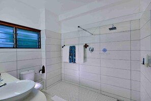 Une salle de bain équipée d’une douche, de toilettes, d’un lavabo et d’une fenêtre avec des stores.
