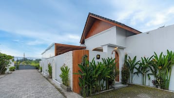 A modern house with a paved driveway, a wooden front door, and a white exterior wall.