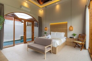 Un dormitorio con cama, sofá, sillón, una mesita, una mesita de noche, una lámpara de pared y vistas a una piscina.