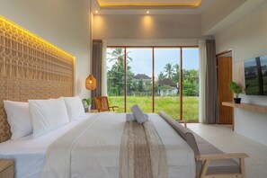A large bed with white linens, a woven headboard, and a view of a lush garden through a sliding door. - Serenia Villa by Betterplace (Ubud)