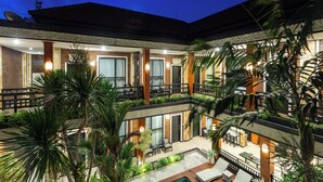 Un hôtel à plusieurs étages doté d’une terrasse, d’une piscine et d  ’une végétation luxuriante.