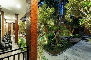 Un patio al aire libre con asientos, piscina y abundante vegetación.