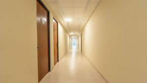 A long, narrow hallway with doors on both sides, a tiled floor, and a ceiling with recessed lighting.