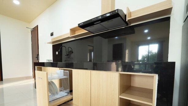 A modern kitchen with a dishwasher, wooden cabinets, and a black countertop.