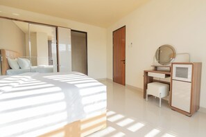 A modern bedroom with a bed, a desk, a chair, a mirror, and a wardrobe.