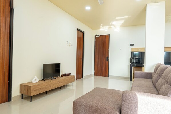 A modern living room with a flat-screen TV, wooden cabinet, and a sofa.