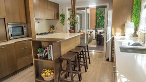 Une cuisine moderne avec des meubles en bois, un four à micro-ondes encastré et un îlot central doté de tabourets.