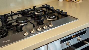 Een keuken met een gasfornuis, oven en bedieningspaneel.