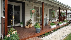 Une véranda en bois agrémentée de plantes en pot, de suspensions florales et de mobilier d’extérieur.