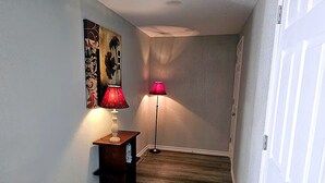 A hallway with a wooden floor, a door on the right, and two lamps on the left.