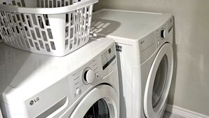 A laundry room with two white LG washing machines and a white laundry basket on top of the left machine.