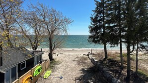 A beach view with a wooden building, a kayak, and a surfboard. - Beachfront Luxury Lake Erie *Sleeps 14* HOT TUB. Great for Hosting Groups (Dunnville)