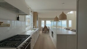 A modern kitchen with a central island, a dining area with a view, and pendant lighting. - Beachfront Luxury Lake Erie *Sleeps 14* HOT TUB. Great for Hosting Groups (Dunnville)