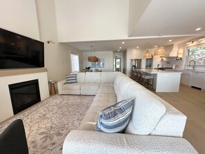 A modern living room with a sectional sofa, a flat-screen TV, and a fireplace. - Beachfront Luxury Lake Erie *Sleeps 14* HOT TUB. Great for Hosting Groups (Dunnville)