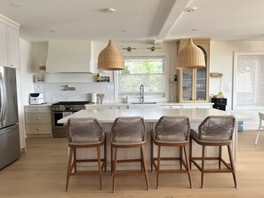 A modern kitchen with a central island, bar stools, and pendant lighting. - Beachfront Luxury Lake Erie *Sleeps 14* HOT TUB. Great for Hosting Groups (Dunnville)