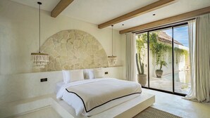 Een slaapkamer met een stenen hoofdbord, een groot bed, uitzicht op een zwembad en een schuifdeur van glas.