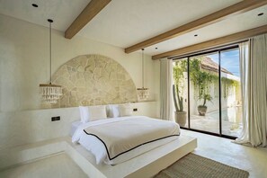 A bedroom with a stone headboard, a large bed, a view of a pool, and a sliding glass door. - Casa Degaz Canggu (Canggu)