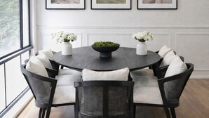 A dining area with a round table, six chairs, and three framed pictures on the wall. - Luxury Country Feel Villa Retreat | Designer Home with elegant features (Wilton)