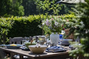 Ein Tisch im Freien mit Blumen, Tellern, Gläsern und einer Karaffe.