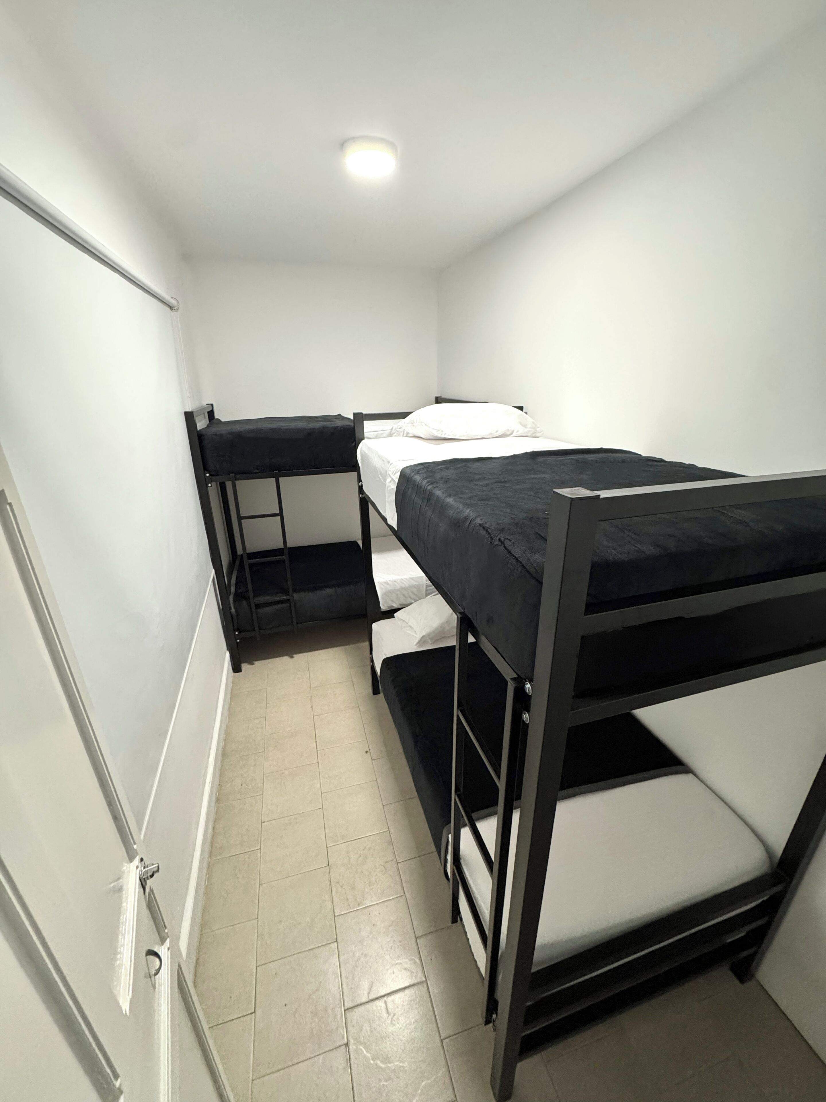 Um dormitório com beliches, um quadro branco e piso de azulejos.
