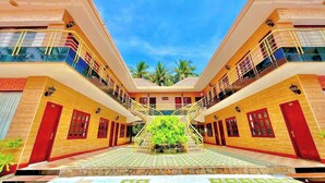 A symmetrical building with a central staircase, multiple balconies, and a tiled courtyard. - Song Bien Xanh Resort (Mui Ne)