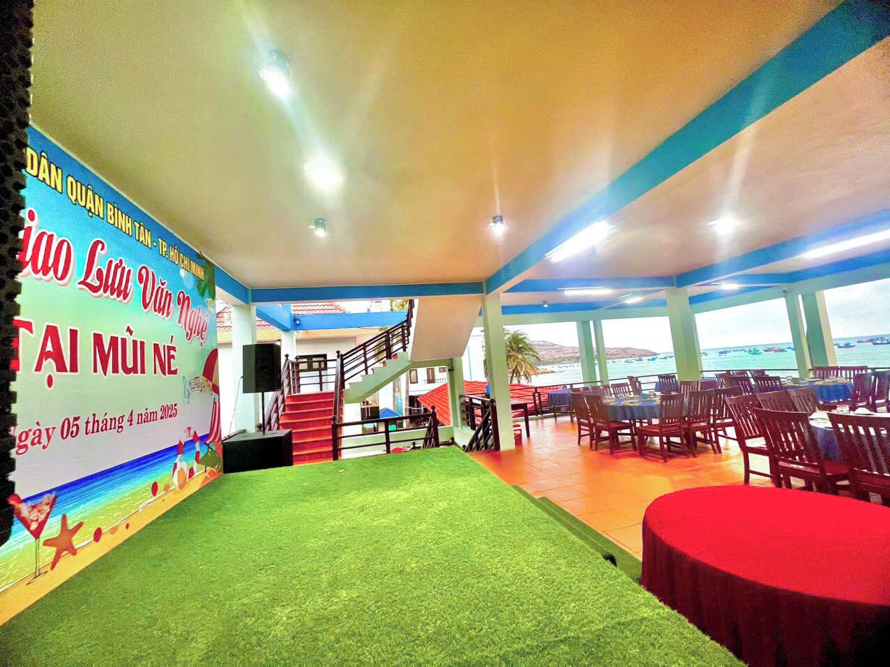 Un salón de conferencias con escenario, asientos y vista al mar.