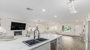 Una cocina moderna con encimera de mármol, electrodomésticos de acero inoxidable y un lavamanos empotrado.