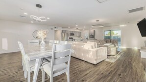 Una sala de estar moderna con comedor, cocina y un ventanal con vistas.