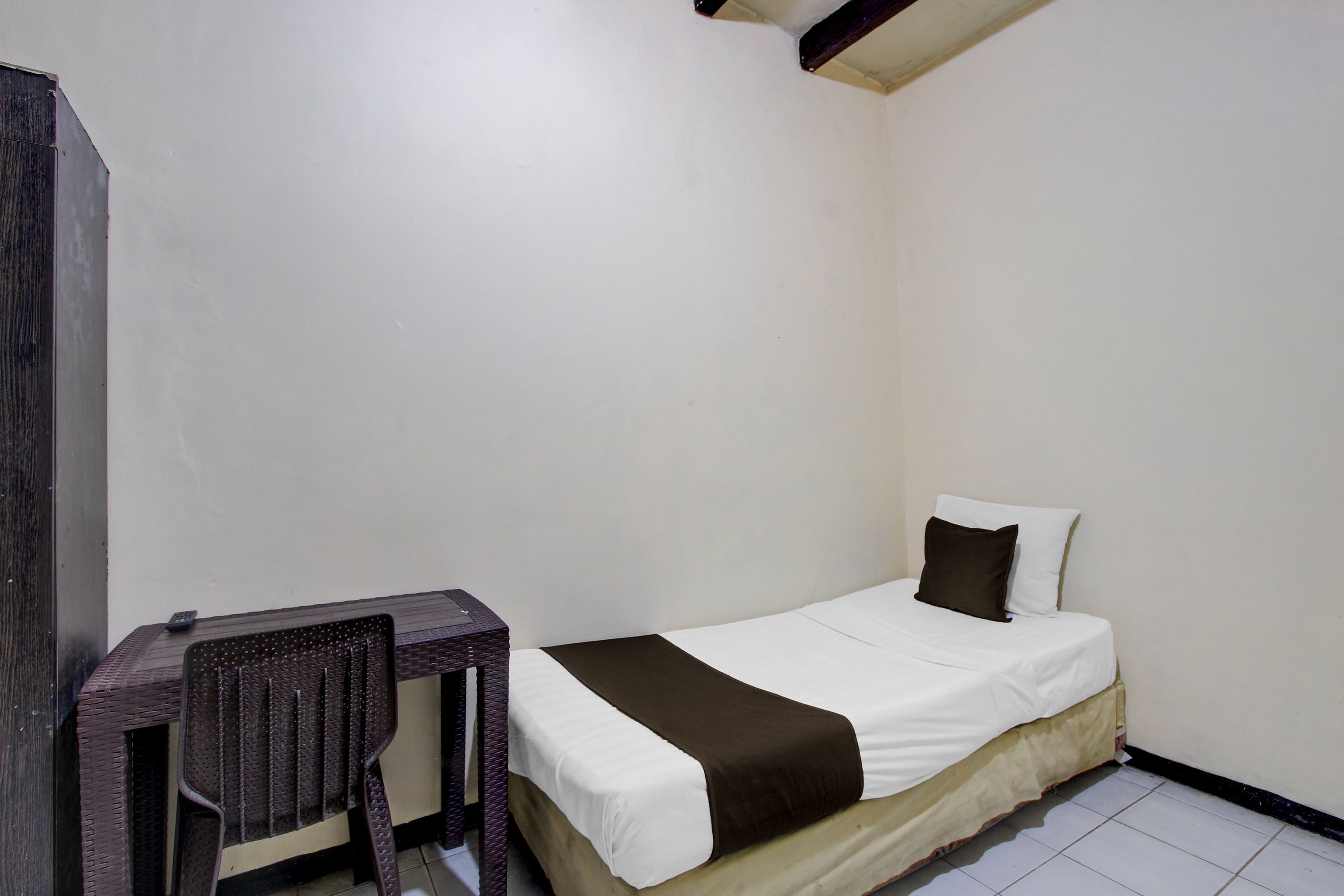 A small, single-bed room with a wooden chair and a desk.