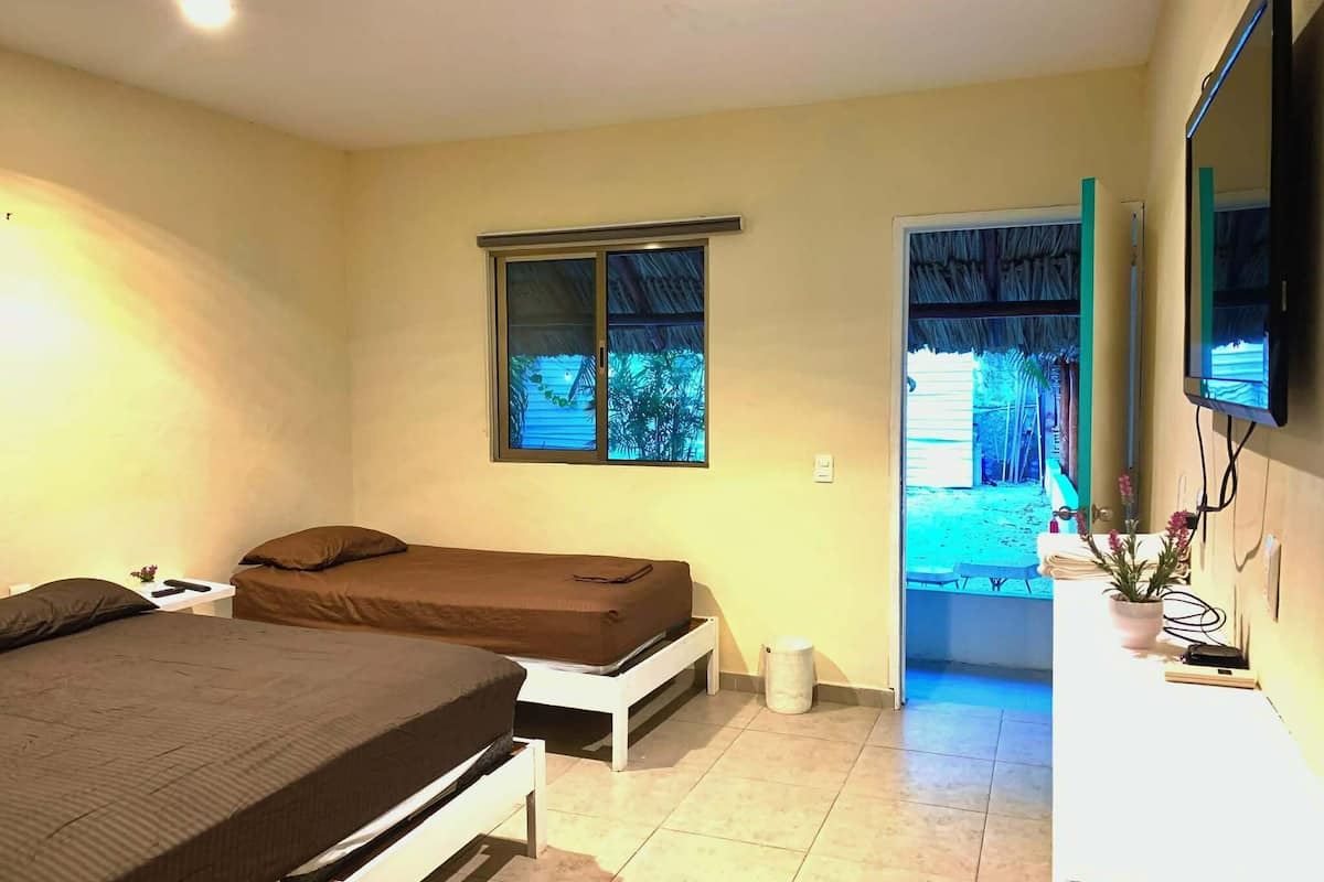 Une chambre avec deux lits, une télévision, une fenêtre et une porte donnant sur l’extérieur.