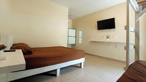 A bedroom with a bed, a bedside table, a TV mounted on the wall, and a small shelf with a plant. - Turquesa Bacalar Centro (Bacalar)
