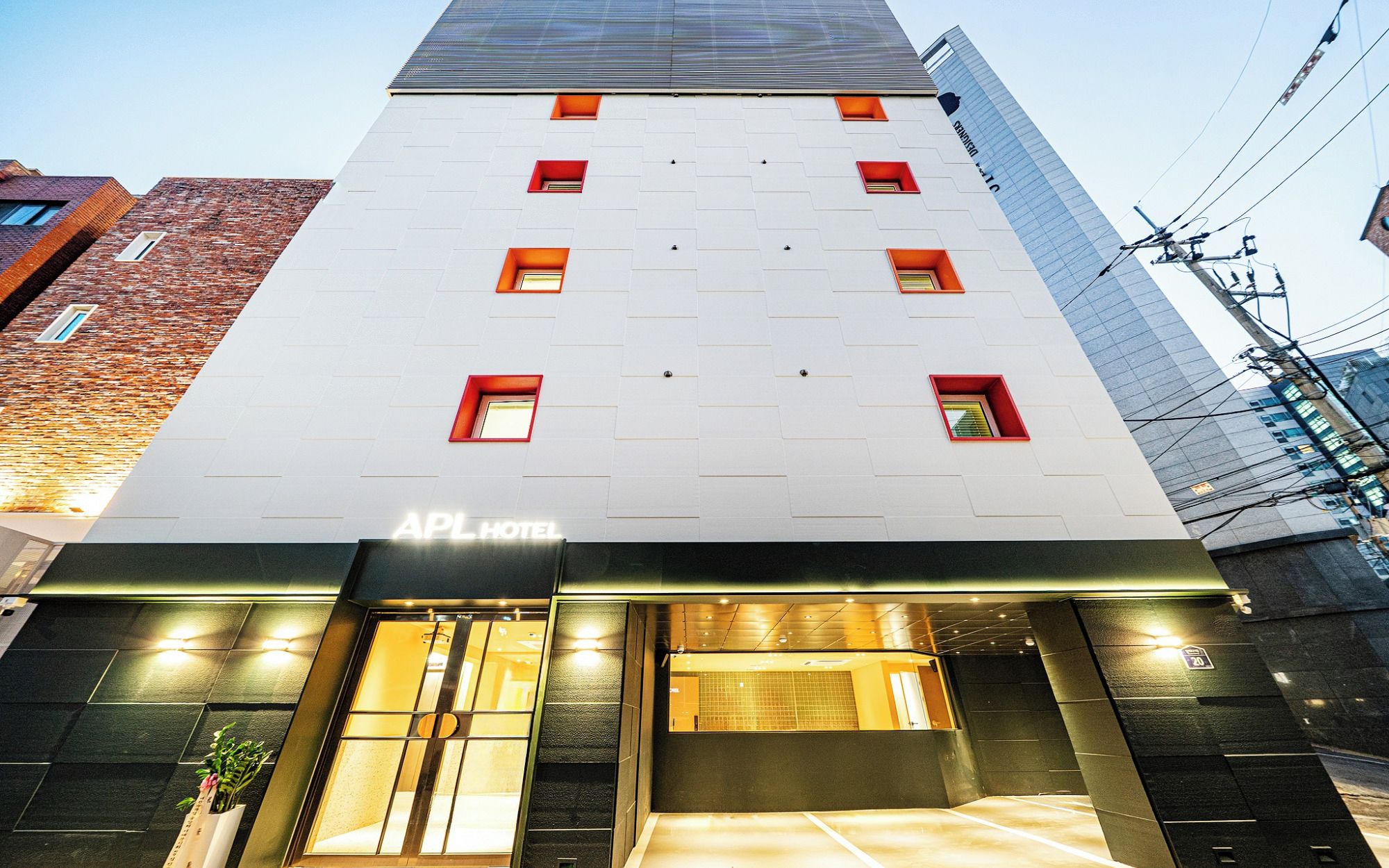 A hotel with a modern facade, multiple windows, and a sign indicating it is the APL Hotel.