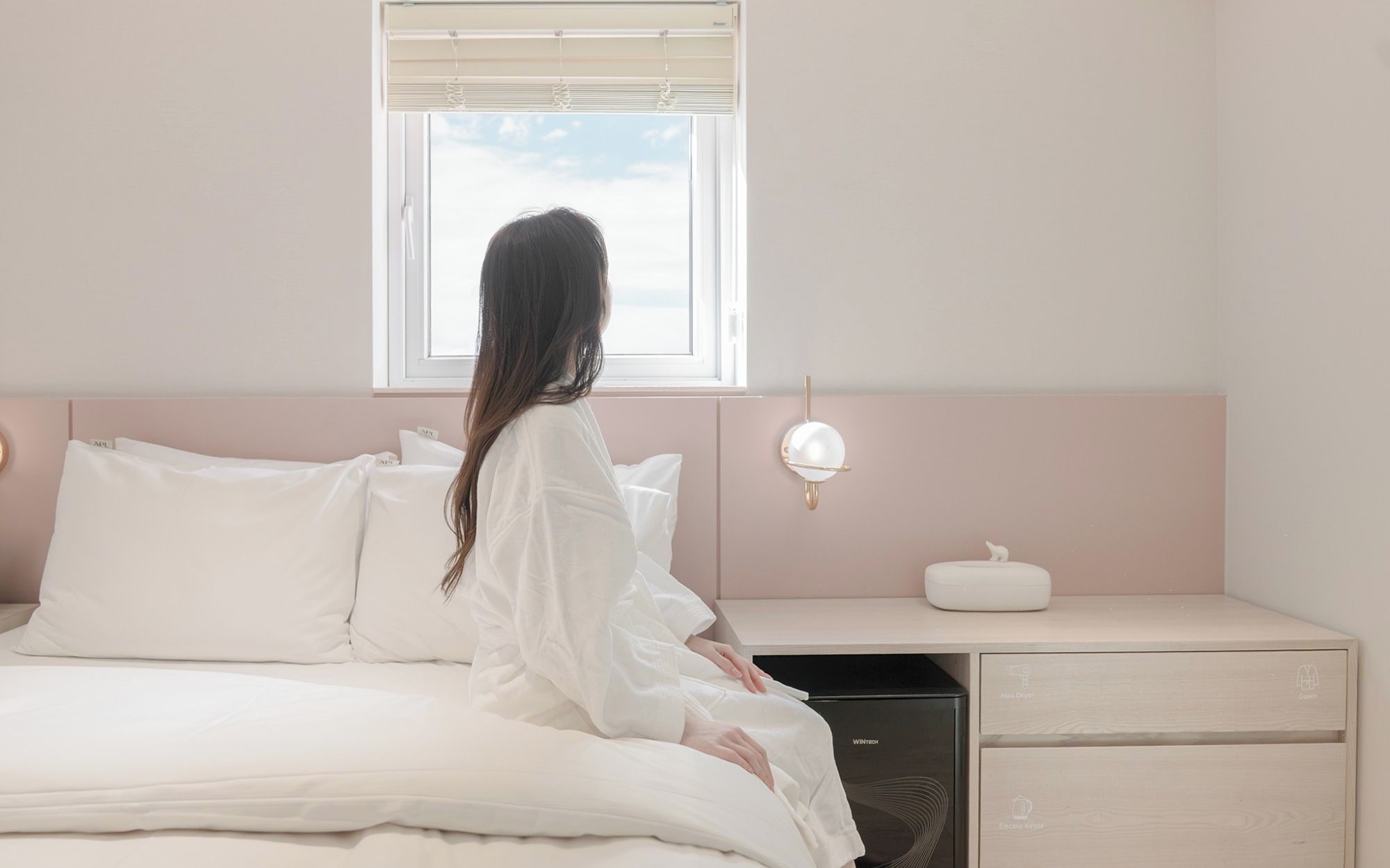 A bedroom with a bed, a bedside table, a lamp, and a window.
