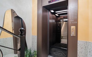 Interior de un ascensor con pantalla digital, panel de control y señalización de los niveles de las habitaciones.