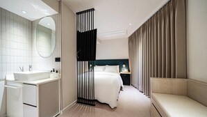 Una camera d'albergo moderna con un letto, un comodino e un'area salotto.