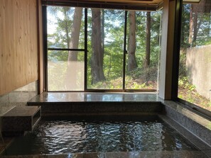 A spa area with a stone bench and a hot tub, surrounded by large windows with a forest view. - Tabinoteitaku Zao Miyagi (Zao)