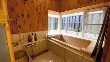 Un bagno in legno con una vasca, una doccia e una finestra.