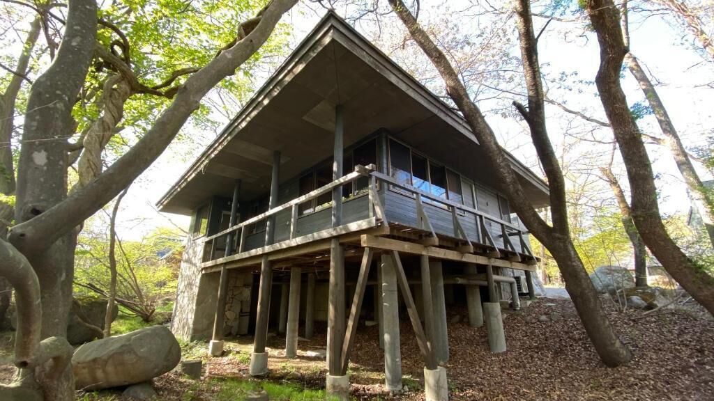 Una cabaña de madera construida sobre pilotes, rodeada de árboles.