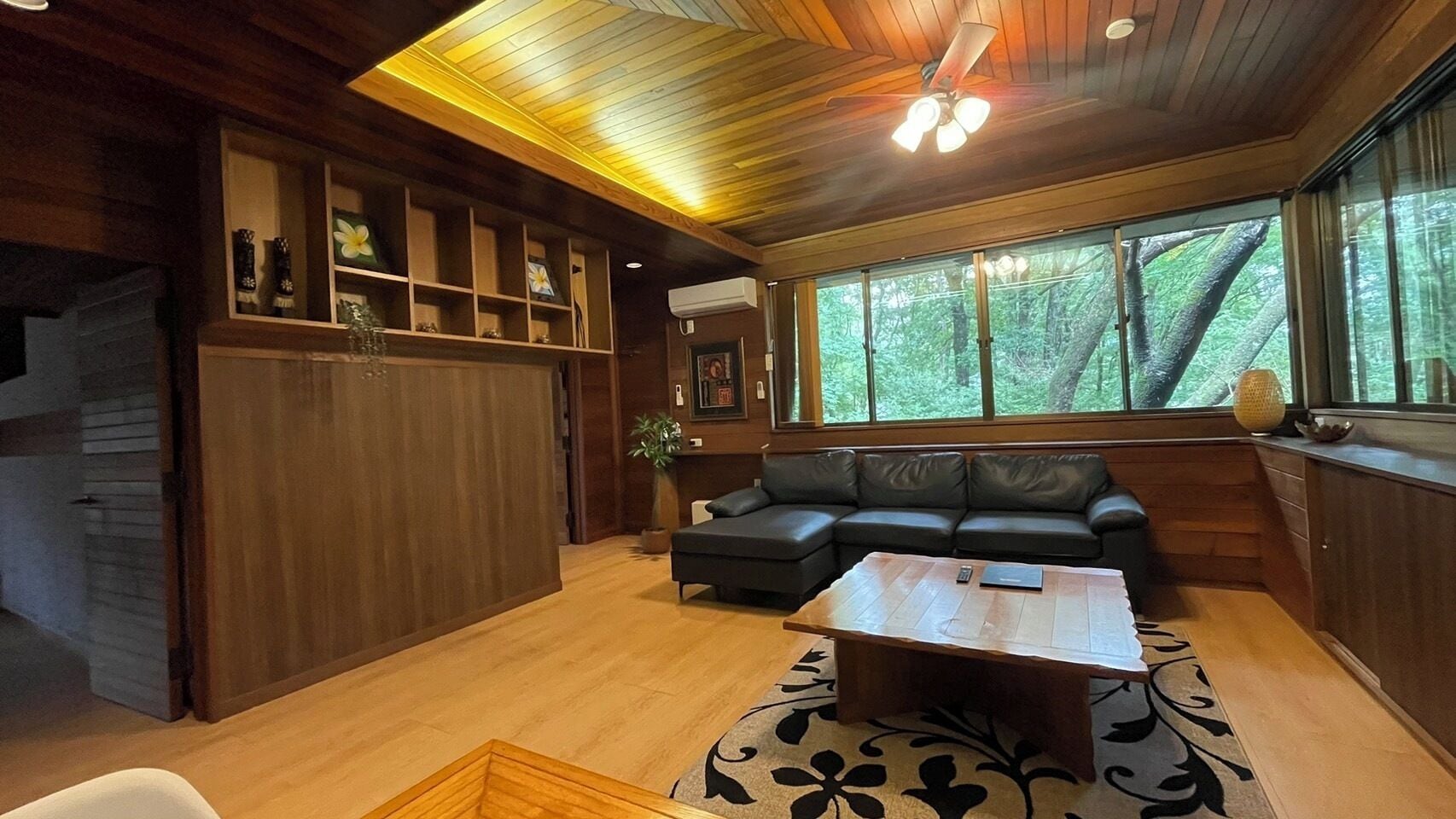 Un salón amplio con techo de madera, un ventanal grande, un sofá y una mesa de centro.