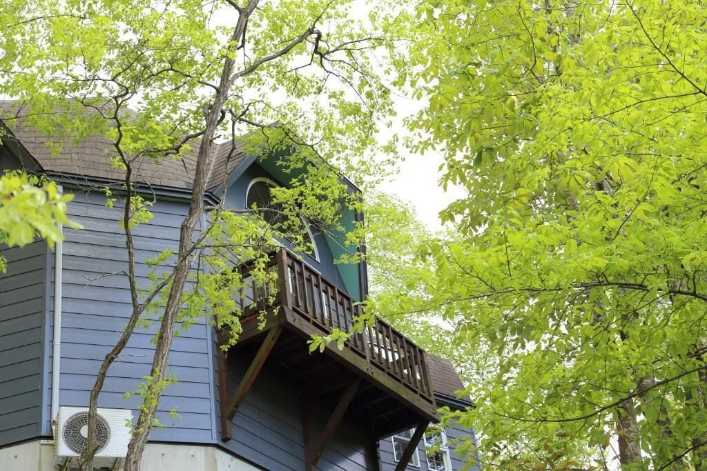 Un edificio con un balcone e un albero di fronte.