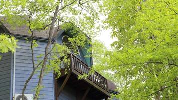 Un edificio con un balcone e un albero di fronte.